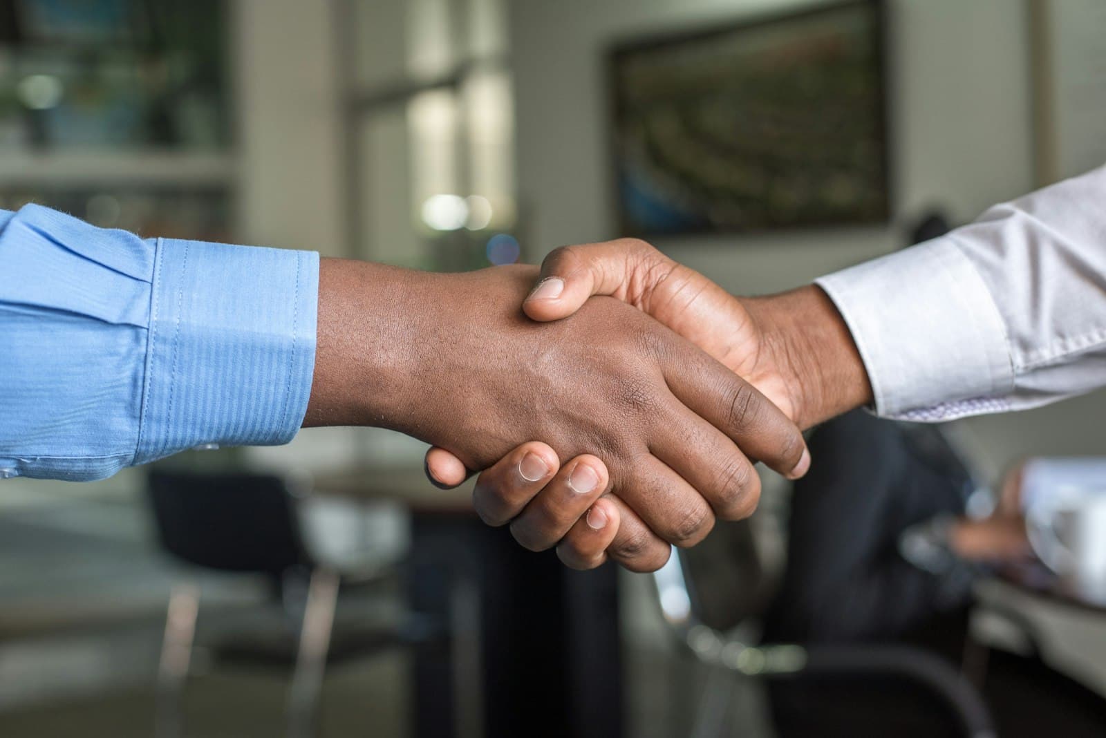 Two business professionals shaking hands across a table, representing an enterprise deal closing